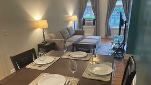Ein Essbereich mit Tisch für vier Personen, einer Couch und Blick ins Freie.