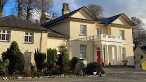 A two-story building with a red door, stone walls, and a gravel driveway. - Lakeview Villa (Liskeard)