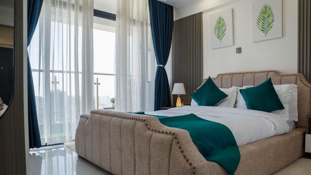 Une chambre d’hôtel avec un grand lit, une table de chevet, une lampe et une vue par la fenêtre.