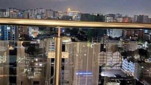 Une vue nocturne d’une ville, avec un immeuble doté d’une grande façade en verre et d’une enseigne verticale bien visible.