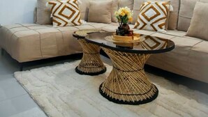 Un salon moderne avec un canapé, une table basse ronde, un lustre et un tableau accroché au mur.
