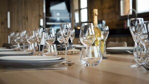 A dining table set with multiple wine glasses and a bottle of white wine.
