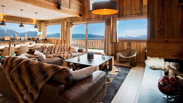 A cozy interior with wooden walls, a dining area, and a view of mountains.