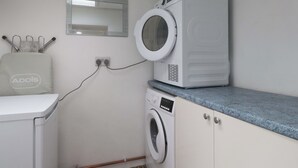 Ett tvättrum med tvättmaskin, torktumlare och en spegel ovanför torktumlaren.
