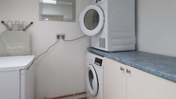 Een wasruimte met een wasmachine, droger en een spiegel boven de droger.