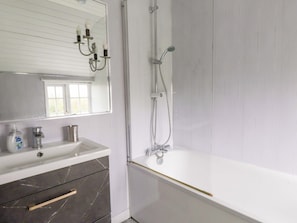A bathroom with a white sink, mirror, and shower. - Ty Crigyll (Holyhead)