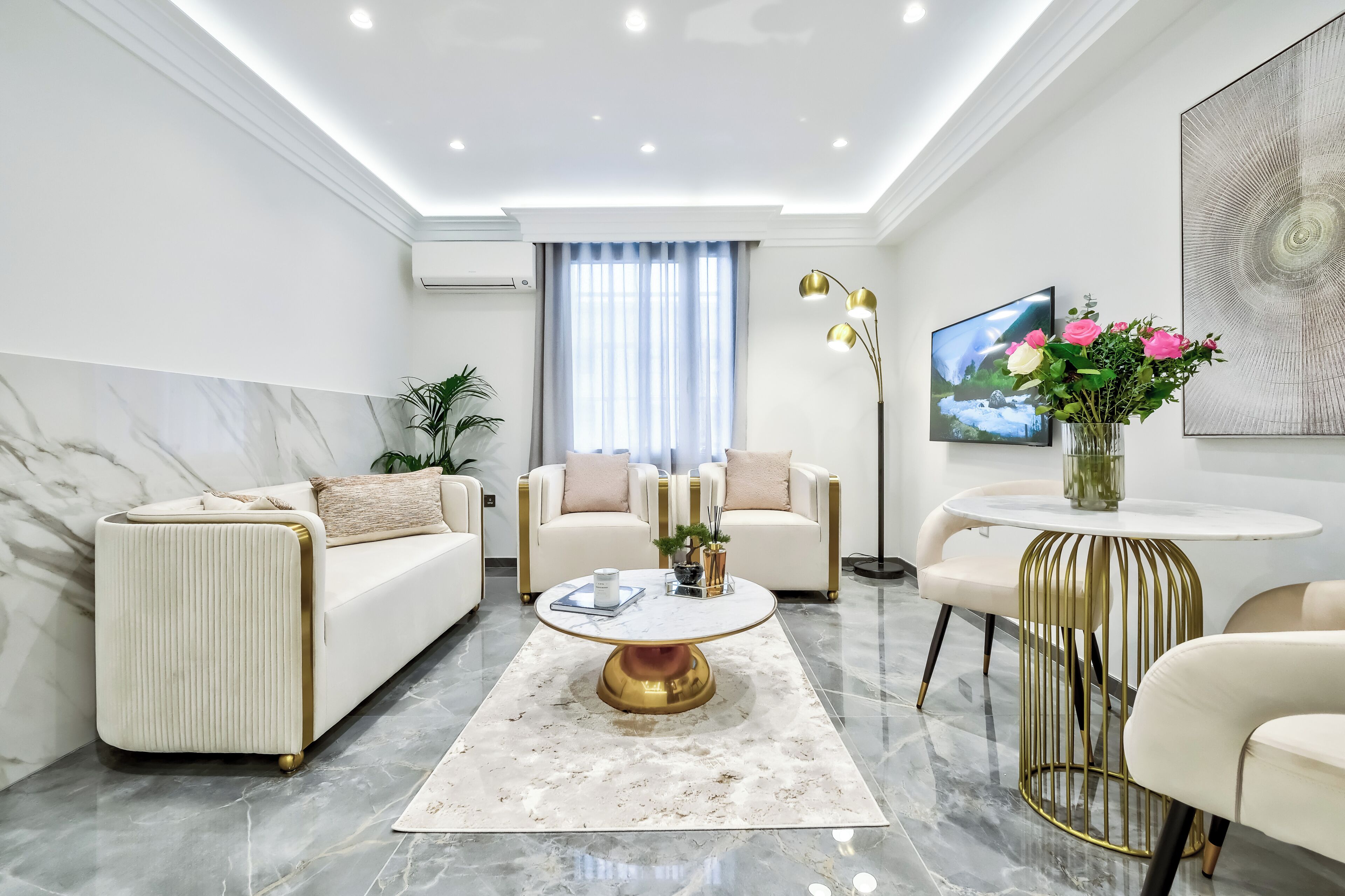 A modern living room with a sofa, armchairs, a coffee table, and a TV.