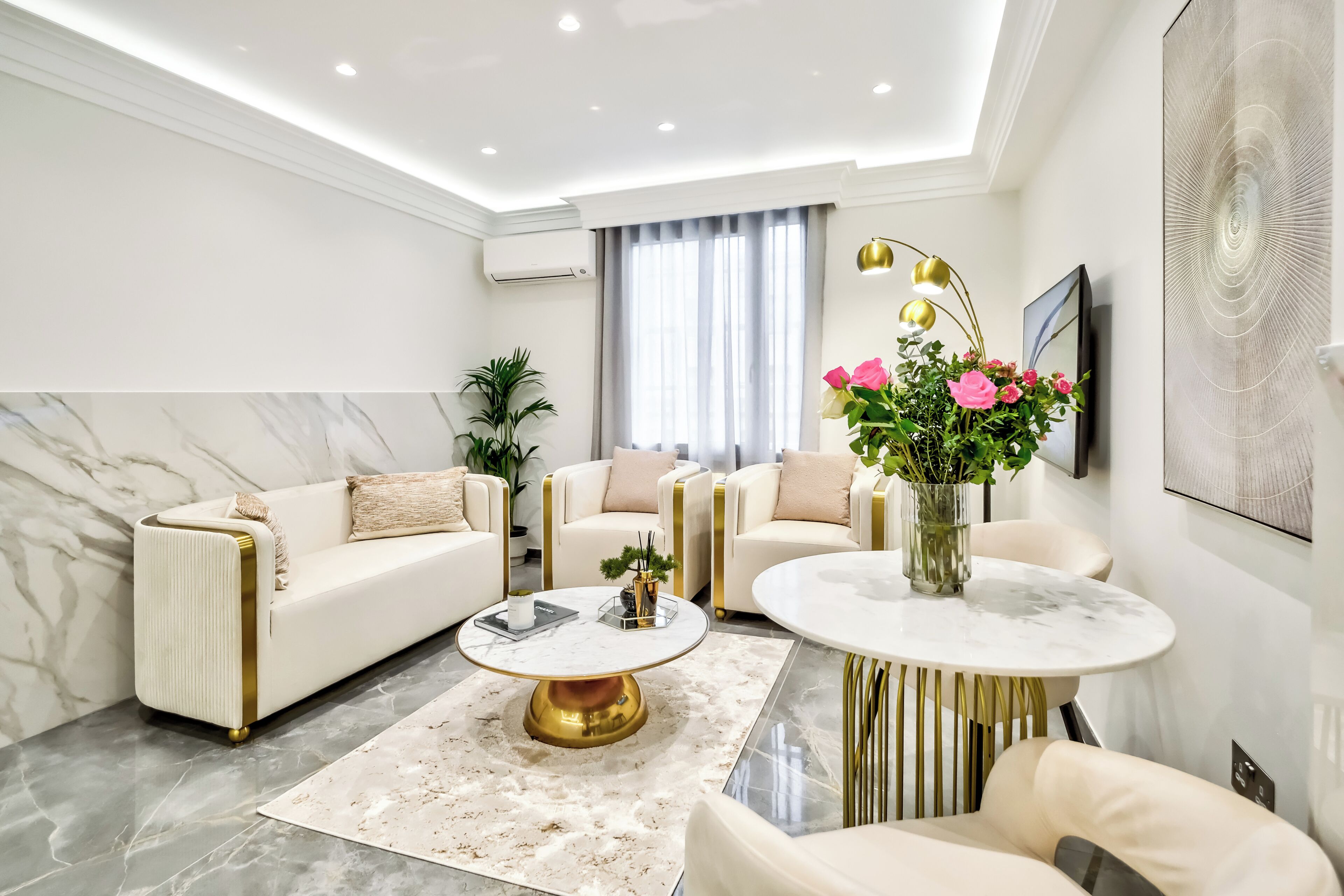 A modern living room with a sofa, armchairs, a coffee table, and a round table.