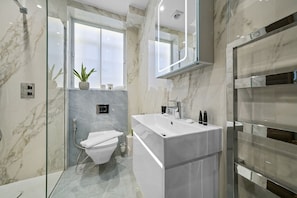 A modern bathroom with a glass-enclosed shower, a white sink, and a marble-tiled floor. - Cumberland Court (London)