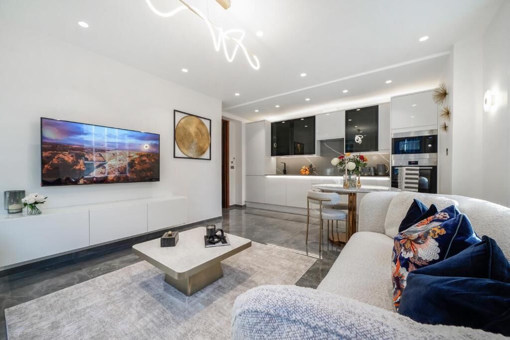 A modern living room with a flat-screen TV, a coffee table, and a sofa with decorative pillows.