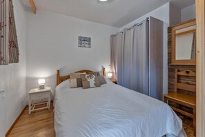 A bedroom with a bed, bedside table, lamp, curtains, and a mirror. - 40m from ski slopes, floor -1, fitness, swimming pool, sauna, balcony, tv, ski locker, 35m² (Les Orres)