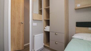 A bedroom with a bed, a wardrobe, a mirror, and a radiator. - The Swift (St Bees)