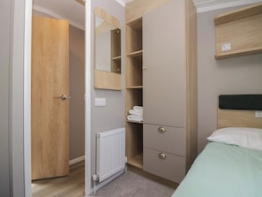 A bedroom with a bed, a wardrobe, a mirror, and a radiator. - The Swift (St Bees)