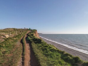 A coastal path with a fence and people walking. - The Swift (St Bees)
