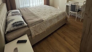 Ett hotellrum med en säng, ett skrivbord, en stol, en TV och en luftkonditioneringsanläggning.