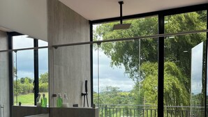 A modern bathroom with a large mirror, a sink, and a view of a balcony with a railing.