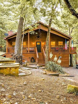 A wooden cabin with a porch, a star on the roof, and a flag.