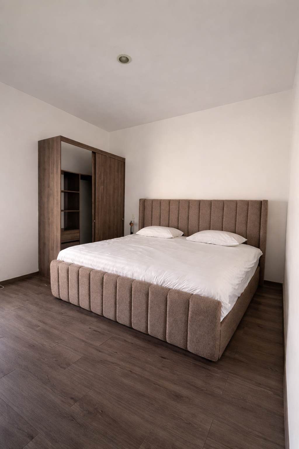 Un dormitorio con cama, armario y una lámpara en el techo.