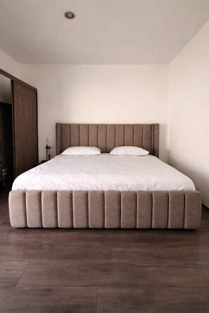A bedroom with a large bed, wooden flooring, and a wardrobe. - departamento totalmente equipado, zona providencia (Guadalajara)