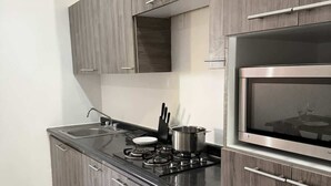A modern kitchen with grey cabinetry, a stainless steel stove, and a built-in microwave. - Totalmente equipado, Zona Providencia, Apartment (Guadalajara)