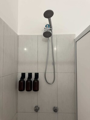 A shower with a handheld showerhead, a flexible hose, and three bottles of shampoo or conditioner on the wall. - departamento totalmente equipado, zona providencia (Guadalajara)