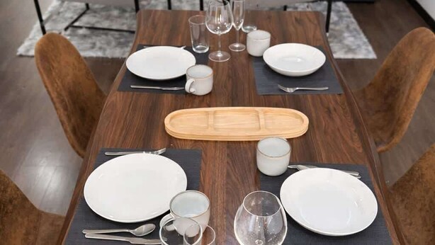 A dining table set with plates, glasses, and cutlery, surrounded by chairs. - Totalmente equipado, Zona Providencia, Apartment (Guadalajara)