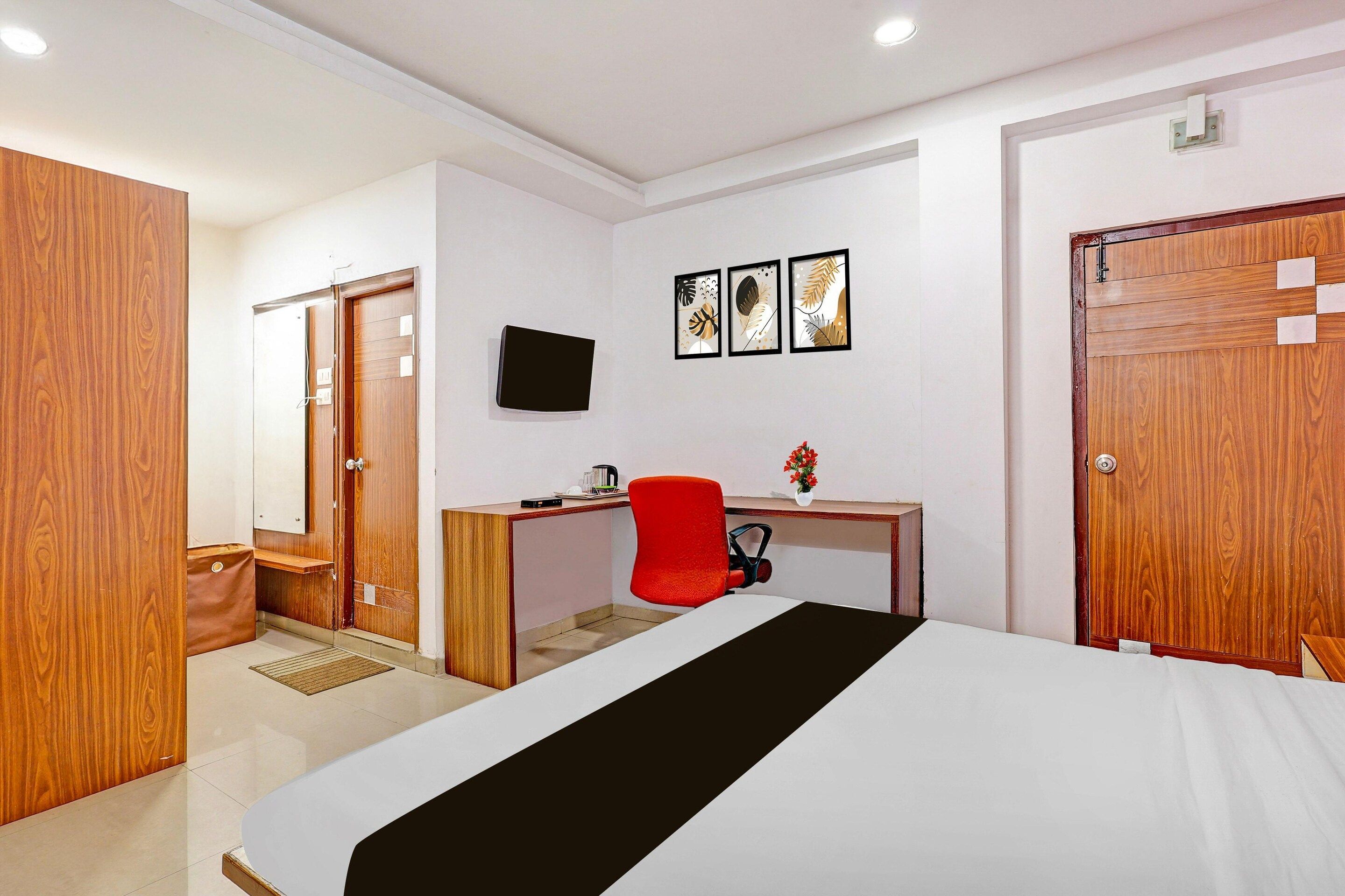 A hotel room with a bed, a desk, a chair, a television, and a wardrobe.