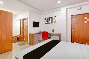 Una habitación de hotel con una cama, un escritorio, una silla, un televisor y un armario.