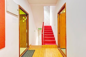 A hallway with a red carpeted staircase, wooden doors, and an exit sign. - Deluxevijaya Residency (Visakhapatnam)