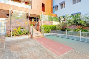 A modern building with a glass entrance, a staircase leading to a second floor, and a gated courtyard with greenery. - Deluxevijaya Residency (Visakhapatnam)