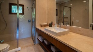 Ein modernes Badezimmer mit Duschkabine aus Glas, einem großen Spiegel und einem weißen Waschbecken.
