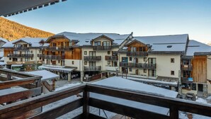 Una stazione sciistica con edifici in legno, balconi e un paesaggio innevato.