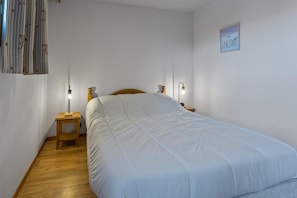 Ein Schlafzimmer mit einem großen Bett, zwei Nachttischen, einem Wandlampen und einem gerahmten Bild.