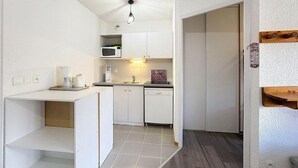 Une cuisine de taille réduite, avec des meubles blancs, un four à micro-ondes, un évier et un lave-vaisselle.