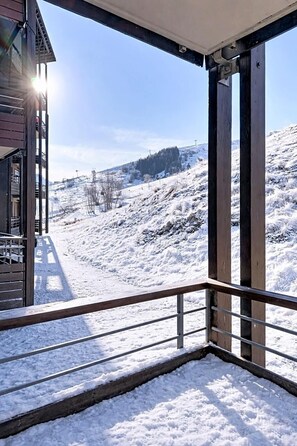 A snow-covered landscape with a wooden balcony and a building in the background. - 200m from resort center, 1st floor, swimming pool, balcony, tv, ski locker, 40m², Le Corbier (Le Corbier)