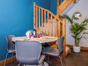A dining area with a round table, four chairs, a bottle of wine, and a potted plant. - The Green (Ripon)