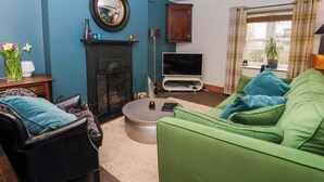 A living room with a fireplace, a television, a sofa, and a coffee table. - The Green (Ripon)