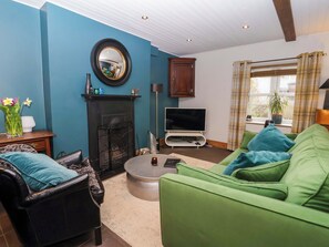 Ein Wohnzimmer mit Kamin, Fernseher, einer Couch und einem Couchtisch.