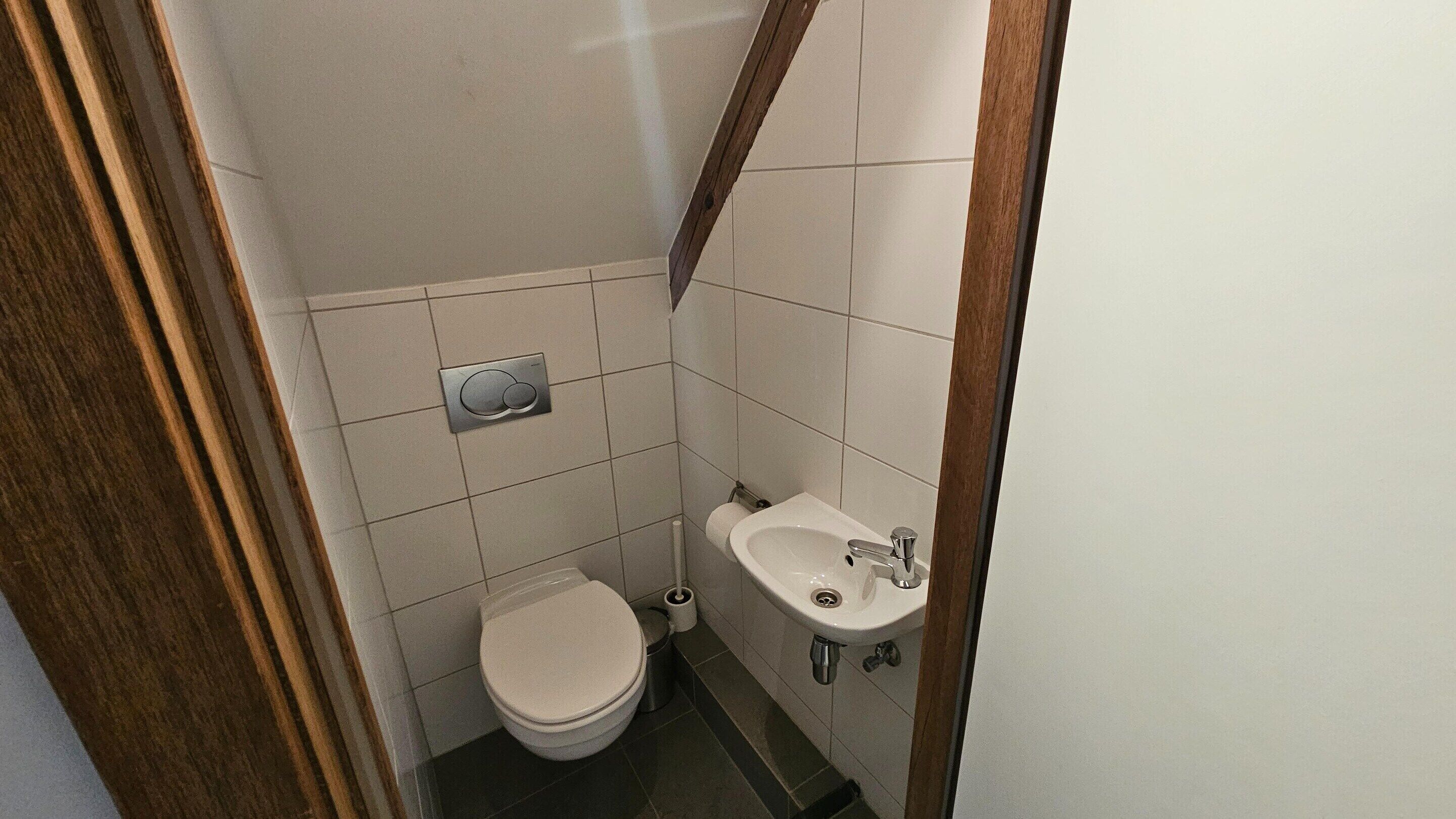 A small bathroom with a toilet, a sink, and a toilet paper holder.