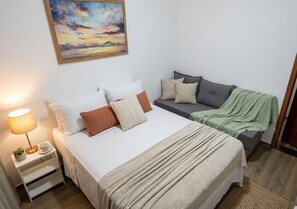 A bedroom with a bed, bedside table, lamp, and a painting on the wall.