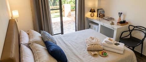 A hotel room with a bed, a desk with a TV, a chair, and a view of the outdoors.