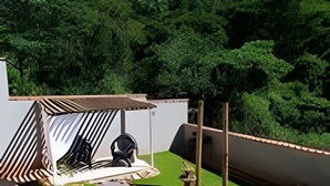 A patio area with a seating arrangement, a small table, and a decorative stone pathway. - Casa da Mata (São Lourenço)