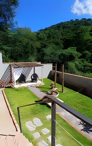 A patio area with a seating arrangement, a small table, and a decorative stone pathway. - Casa da Mata (São Lourenço)