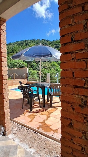 Un patio con piscina, mobiliario exterior y vistas a las colinas.