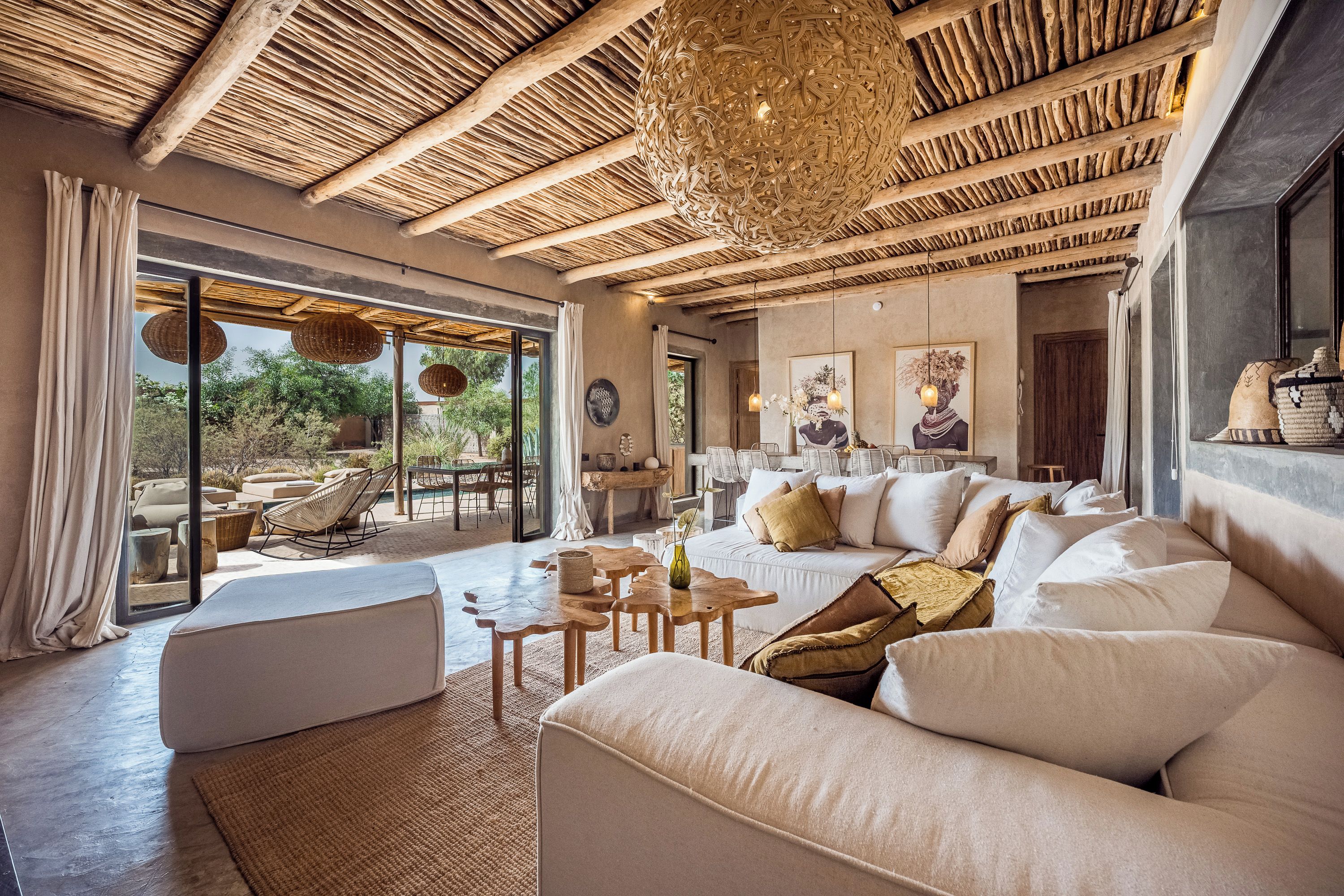 A spacious living area with a large sofa, a dining table, and a view through a glass door to an outdoor patio.