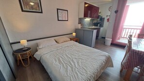 Ein Schlafzimmer mit Bett, Nachttischen, einer kleinen Küchenzeile und einem Esstisch.