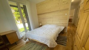 A bedroom with a wooden headboard, a bed with white bedding, a wooden desk, and a green striped rug. - 100m from ski slopes, Ground floor, tv, 80m², Pra Loup (Pra Loup)