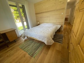 A bedroom with a wooden headboard, a bed with white bedding, a wooden desk, and a green striped rug. - Ground floor, tv, 80m², Pra Loup (Pra Loup)