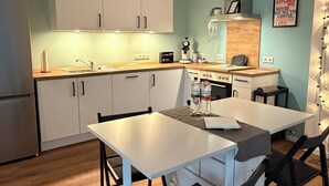 Una cocina moderna con armarios blancos, una mesa de comedor con sillas y una isla de cocina.