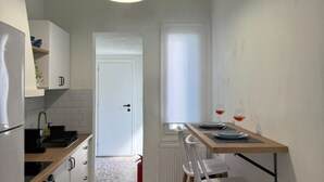 Eine schmale Küche mit weißen Schränken, einer Holzauskładung, einem Spülbecken und einem Essbereich mit Tisch und Stühlen.